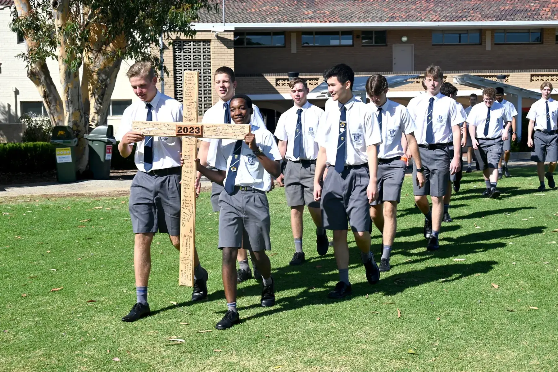 A photo of year 12 students walking with the cross that they all sligned.